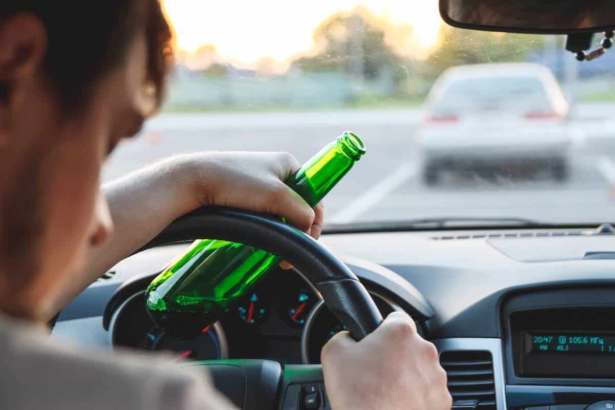 mann-mit-bierflasche-am-lenker-eines-autos