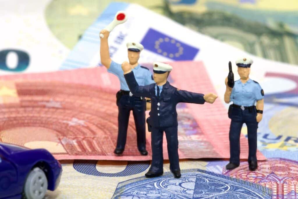 euroscheine-auf-denen-polizisten-figuren-stehen-die-auto-zur-verkehrskontrolle-anhalten
